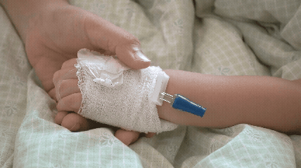 Vídeo curto decorativo animado, sem som e repetitivo, de uma mão adulta segurando a mão com acesso venoso de uma criança que está doente no hospital.