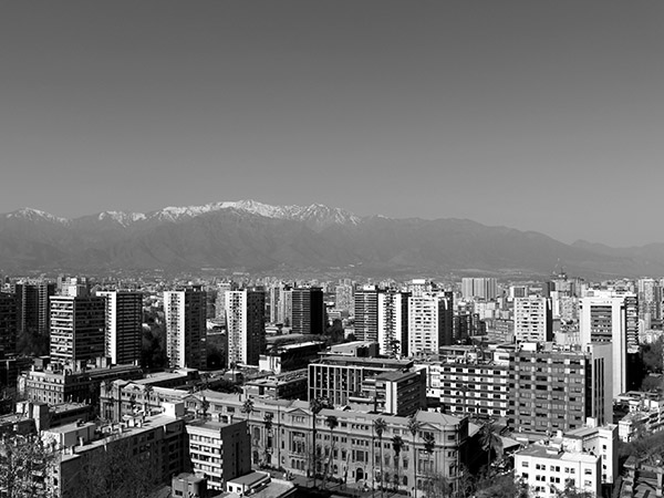 Fotografia de uma cidade, vista de longe, com montanhas ao fundo.